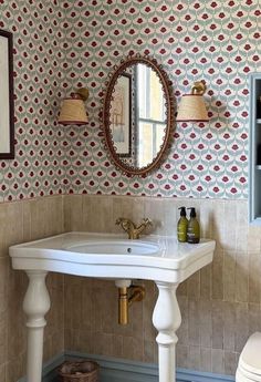 a white sink sitting under a mirror in a bathroom next to a wall mounted toilet