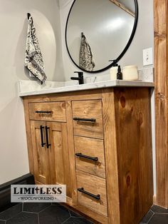 a bathroom vanity with a round mirror on the wall above it and wooden drawers underneath