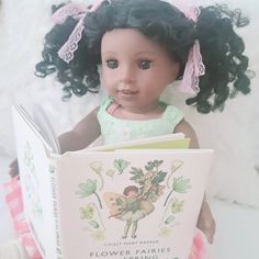 a doll holding a flower fairy book in her hands