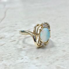 CLEARANCE - 40% OFF! Lovely vintage 14 karat yellow gold ring featuring an oval opal cabochon weighing approximately 1/2 carat, and 4 single cut diamonds weighing approximately 0.06 carat.The diamonds are near colorless and are slightly included to Included. Ring size 6.25 US / M UK / 52 FR. > Ring sizing not included.This ring can be sized to fit most fingers.If you need to size this ring, please contact us before placing the order.Sized rings are final sale. Our minimum sizing fee is $29 for y Classic Yellow Gold Opal Ring With Center Stone, Oval Opal Birthstone Ring, Gold Opal Ring With Oval Cabochon, Opal Cabochon Ring In 14k Gold For Anniversary, Opal Rings In Yellow Gold With Diamond Accents, Heirloom Opal Oval Rings, Heirloom Oval Opal Ring, Heirloom Opal Ring With Diamond Accents, Oval Opal Ring In Yellow Gold Stamped 14k