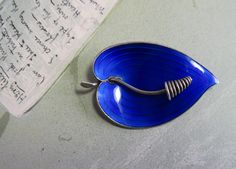 a blue bowl with a spoon in it sitting on a table next to a piece of paper