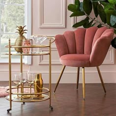 two pink chairs and a gold bar cart in a living room with wood flooring