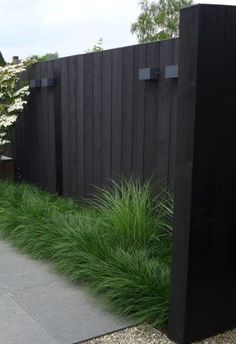 a black fence with tall grass next to it