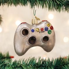 an ornament shaped like a video game controller hangs from a christmas tree branch