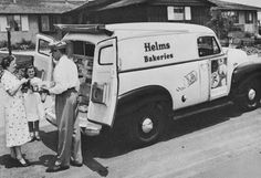 an old black and white photo of people standing in front of a van with the back door open