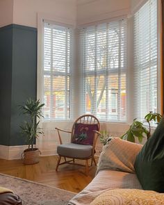 a living room filled with furniture and windows covered in white blinds on top of them