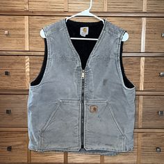 Faded Handsomely And Distressed By Hard Work, This Men’s Carhartt Vest Is Ready To Get Rowdy! Faded Gray Color With Original Zipper/Carhartt Decal. Sherpa Inside And Drop Back For Warmth And Two Inside Pockets. Great For Layering. This Carhartt Vest Will Last To Be Passed Downa Few More Times! Sanitized For Your Comfort. Put To Pit 22” And Top Of Shoulder To Bottom Of Front Hem 24”. Workwear Vest, Carhartt Vest, Carhartt Men, Carhartt Jackets, Men Carhartt, Carhartt Mens, Mens Vest, This Man, Hard Work