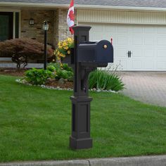 a mailbox in front of a house with a flag on the post and flowers