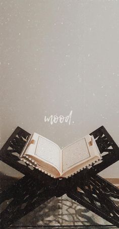 an open book sitting on top of a wooden table next to a wall with words above it