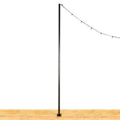 a black pole with some lights on it and a white wall in the back ground