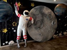 an astronaut standing on a ladder next to a giant moon and stars mural in a room