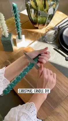 a woman is holding a knife on a table with christmas decorations in the background and text overlay that reads, christmas candle diy