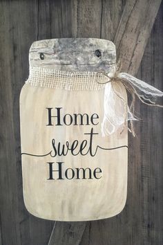 a mason jar with the words home sweet home on it hanging from a wooden fence