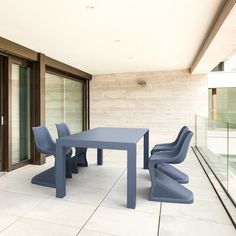 a black table and chairs sitting on top of a white tile floor next to sliding glass doors