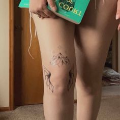 a person with tattoos on their legs holding a book