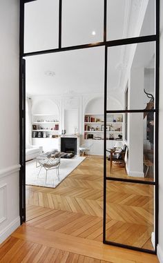 an open door leading to a living room with wood floors and white walls in the background