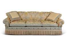 an ornate couch with fringe trim and pillows on it's back, against a white background