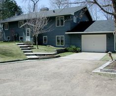 a large gray house with steps leading up to the front door and two garages