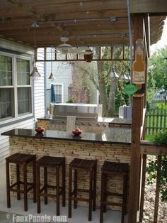 an outdoor kitchen with bar stools and grill