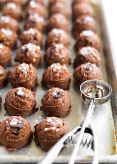 chocolate muffins are on a baking sheet with a spoon and fork next to them