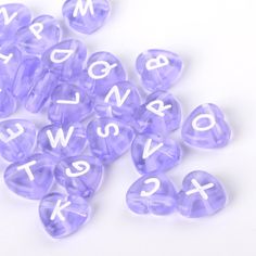 purple dices with white letters and numbers are scattered on a white surface, as if they were made out of plastic