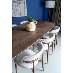 a wooden table with white chairs and a potted plant sitting on top of it