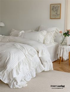 a white bed with ruffled sheets and pillows