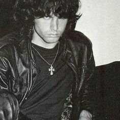 a young man with long hair wearing a leather jacket