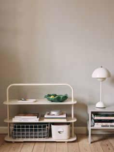 a white shelf sitting next to a lamp on top of a wooden floor