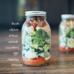 two mason jars filled with food sitting on top of a wooden table