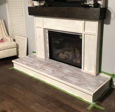 a living room with a white fireplace and green tape around the mantles that are taped together