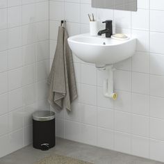 a white sink sitting next to a mirror in a bathroom under a faucet