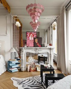 a living room filled with furniture and a fire place under a pink chandelier