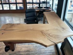 a wooden desk in an office with black chairs