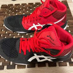 a pair of red and black running shoes sitting on top of a wooden floor next to each other