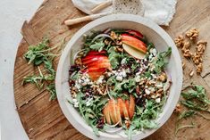 an apple and walnut salad in a white bowl on a wooden cutting board next to some bread