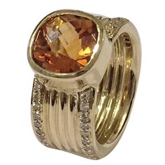 a gold ring with an orange topazte and white diamonds on the bottom, set in