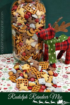 a glass jar filled with christmas treats next to a reindeer figurine on a table