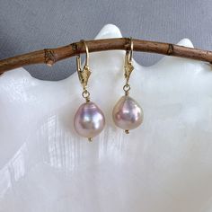 "✦These large and beautifully paired freshwater Edison pearl earrings have a beautiful luster and baroque flame ball shape, with iridescent blush pink or dusty rose color.  The pearls are wire wrapped to 14k gold filled lever back ear wires. The freshwater pearls measure 11mm in diameter and total length is a little less than 1.5\" in length. ✦Available with your choice of 14k gold filled French hook, Fleur de Lis or plain leverback ear wires. Please select at check out. ✦Click here to see these earrings in sterling silver: https://www.etsy.com/listing/1650340050 ✦What is an Edison Pearl? An Edison pearl is a type of freshwater cultured pearl known for its large size, lustrous surface, and unique colors. These pearls are cultivated using a technique that involves grafting a small piece of Formal Single Baroque Pearl Earring, Single Drop Baroque Pearl Earring, Delicate Handmade Baroque Pearl Earrings, Single Dangle Baroque Pearl Earring, Gold Delicate Baroque Pearl Earrings, Freshwater Mussels, Pink Pearl Earrings, Brazilian Gold, Dusty Rose Color