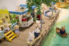 some toy animals are playing in a fake water park with palm trees and people on boats