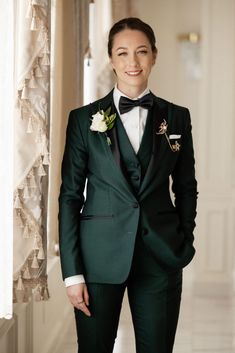 a woman in a green tuxedo and bow tie standing next to a window