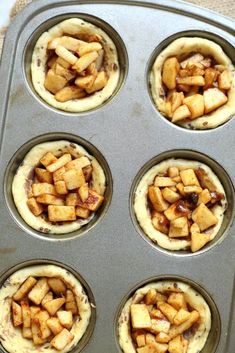 an uncooked muffin tin filled with mini apple pies