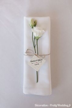 two white flowers are placed on top of a folded napkin