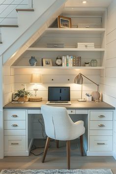 a desk with a computer on top of it under a stair case in a home office