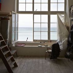 an empty room with a large window and ladders in front of the window looking out onto the ocean