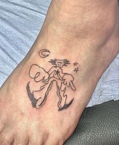 a person with a tattoo on their foot that has an image of a cat and moon