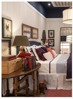 a bed room with a neatly made bed next to a wooden table and lamps on the wall