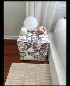 a white and black marble table next to a bed