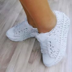 a person wearing white shoes with pearls on them