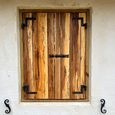 a wooden door with iron handles on a white wall